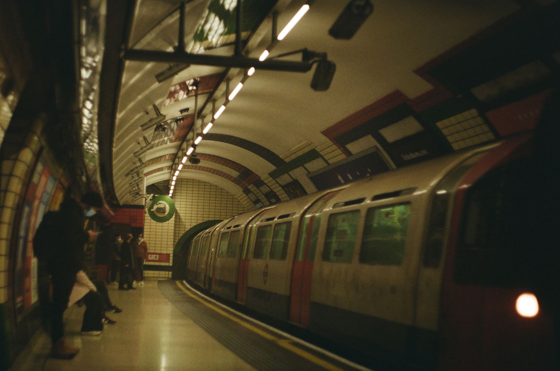 Peron aglomerat de metrou londonez London Underground cu un tren care soseste